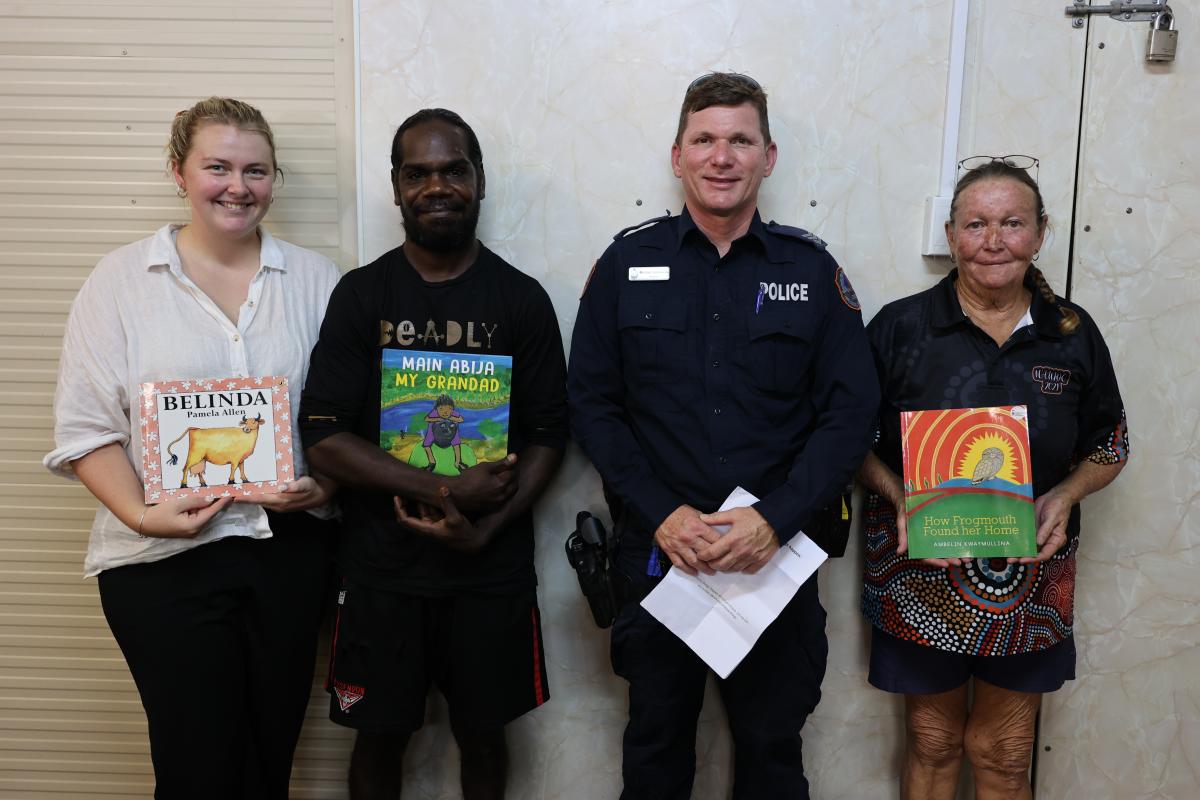 4 people standing next to each other holding up a book