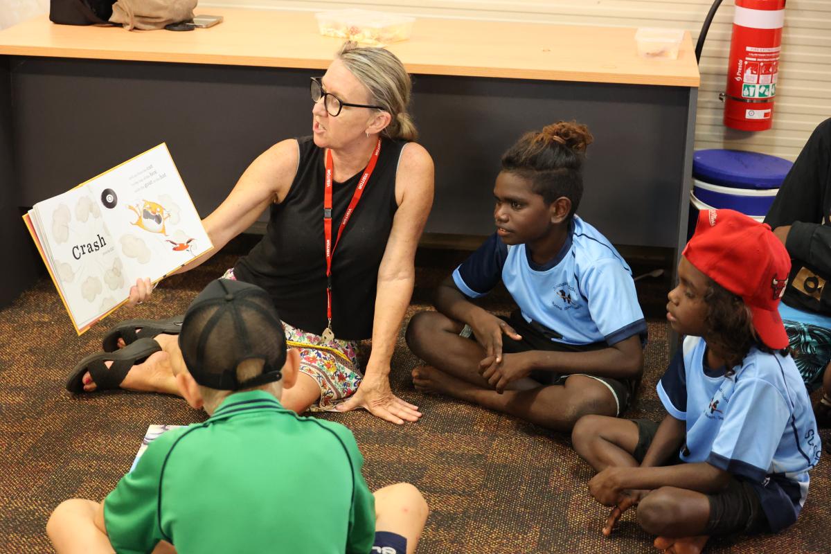 4 people reading a book on the floor