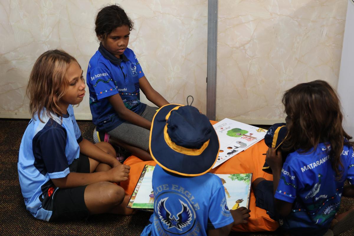 4 students reading a book on floor