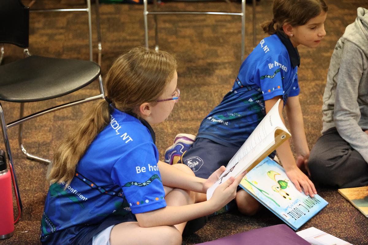 2 students reading books on the floor