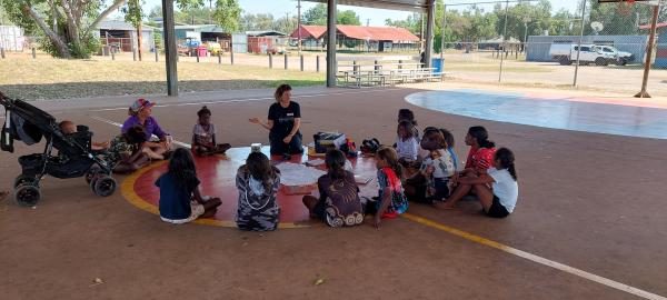 Children sitting on basketball court drawing pictures