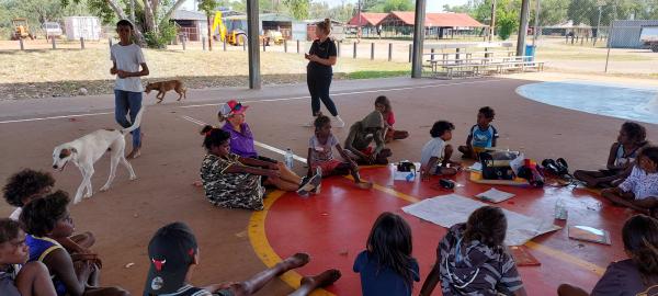 Children sitting on basketball court drawing pictures