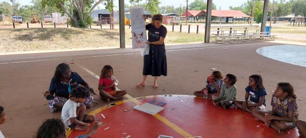 Children sitting on basketball court drawing pictures
