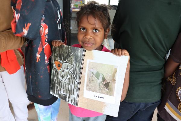 Young girl holding up book with dog picture