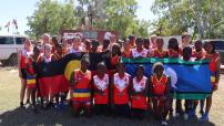 Two football teams holding flags for NAIDOC